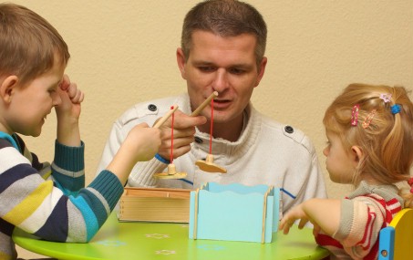 Vater beim Angel-Spiel mit Kindern am Tisch