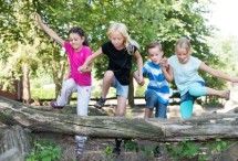 Kinder und Jugendliche springen über Baumstamm