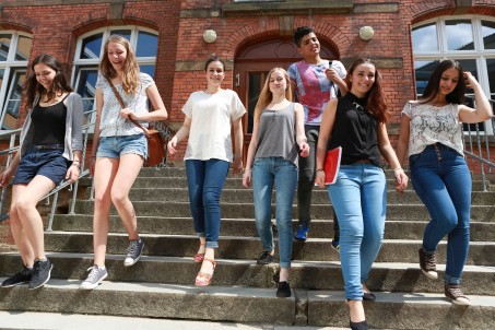 Sieben junge fröhliche Menschen gehen dynamisch eine Treppe hinunter.