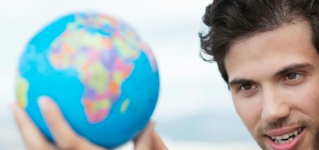 Junger Mann sieht auf eine Weltkugel