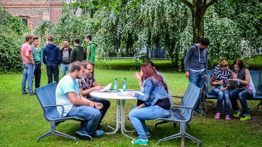 Jugendliche im Garten, stehend und am Tisch sitzend, entspannte Atmosphäre