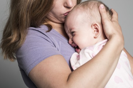 Mutter mit weinendem Kind auf dem Arm.