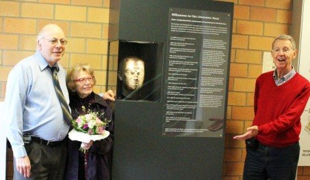 Marieli Rowe (Mitte mit Blumenstrauß) mit Sohn Peter Rowe (links) und Neffe Professor Dr. Raimund Wimmer stehen vor der Statue des berühmten Psychiaters Löwenstein im Eingangsbereich des Otto-Löwenstein-Hauses.